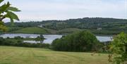 Image is of a field and lake surrounded by the countryside