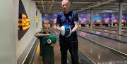 A man and young boy on the bowling alley.