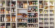 A wall covered with shelves of sauces, spreads and other food products.