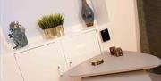 A small table in a corner with coasters and a cabinet with decorations.