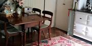 Image shows kitchen dining area with table and four chairs plus Aga