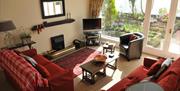 Living room with two red sofas, a chair, a fireplace, a TV and a large window with patio doors.