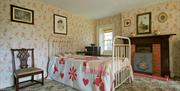 A historic bedroom with a chair and a fireplace.