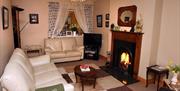 A living room with cream sofas, fireplace, TV and patterned rug