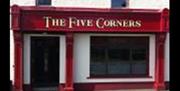 A red sign for The Five Corners with a window and a front door.