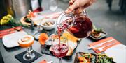 A server pouring sangria into a wine glass on a set dining table.