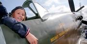 a boy sits in the seat of an old airplane