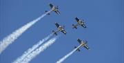 four airplanes perform a synchornised aerial display in the sky