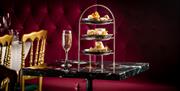 A plated afternoon tea stand on a table with a glass of champagne.