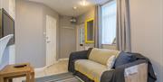 A photo of a living room area with a sofa and TV leading to a front door.