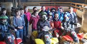 Image is of a group of children with some on mini quad bikes