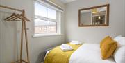 A double bedroom with a mirror, window and a clothes hanging area.