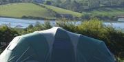 Image is of a large tent with lake view behind