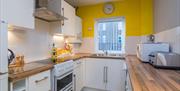 A photo of a kitchen with an oven, sink, microwave, toaster and a window.