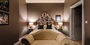 Image shows double bedroom with a small sofa at the foot of the bed. Doorway open onto ensuite