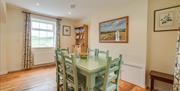 A large dining room with a green table and chairs and a window.