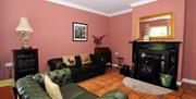 Image shows lounge area with tiled floor, leather sofas and fireplace