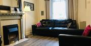 A living room with a black sofa and chair, a fireplace and a standing lamp.