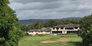 Image is of golf course with club house in the background