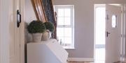 Image shows hallway with wooden floor and front door open unto outside area