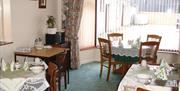 Image shows dining room of property with large window looking out onto courtyard