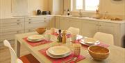 Dining room table fully set with crockery, cutlery, salad bowls and salt & pepper shakers.