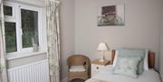 Single bedroom with window outlooking greenery.  Wooden chair at the side of the bed