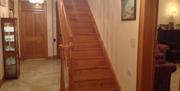 A hallway with a wooden staircase leading to a door.