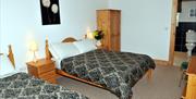Image shows 2 double beds in room with wardrobe and door open to show ensuite