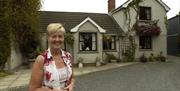 Lady standing smiling in front of exterior of house