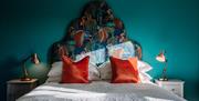 Image shows double bed with cushions and beside tables with lamps