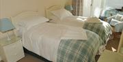 Bedroom with two single beds, bedside drawers and a chair.