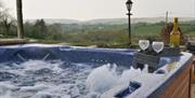 hot tub with a bottle of wine and 2 glasses.  Scenic mountain view in background