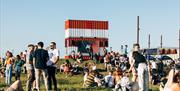 Red and white shipping containers and people on the grass