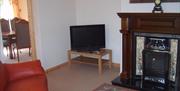 sitting room with a red chair, TV, fireplace and a doorway to the dining room.