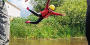 Child jumping into the water and creating a star shape, having fun on summer camp