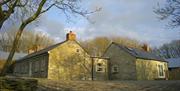 A corner view of a stone cottage with two sections.