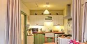 A kitchen area with a fridge, cooker, Belfast sink and a microwave.