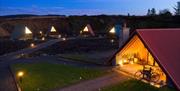 image of glamping pods at night, bicycle on porch