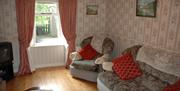 A sitting room with a suite, a window and a tv.