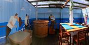 A photo of an outdoor deck with murals of couples on the Titanic, wooden furniture, and a large hot tub in the center.