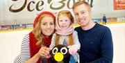 Image is of a couple and small child on the ice rink