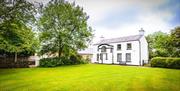 Image is of side view of property with lawn in front and trees to each side