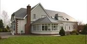 Side view of a lodge with a large conservatory and a garden.