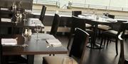 Dining area with set tables, and a large window overlooking a road and the lough.