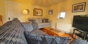 Living room with sofas, a coffee table, a mirror, a TV and a small window.