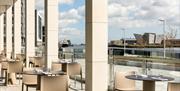 A semi-outdoor dining area with a view of Belfast's docks and the Titanic building.