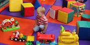 Indoor play area with child on mat surrounded by toys