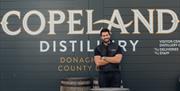 A man standing in front of Copeland premises signage