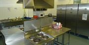 A photo of a restaurant kitchen with cookers, sinks and fridges.